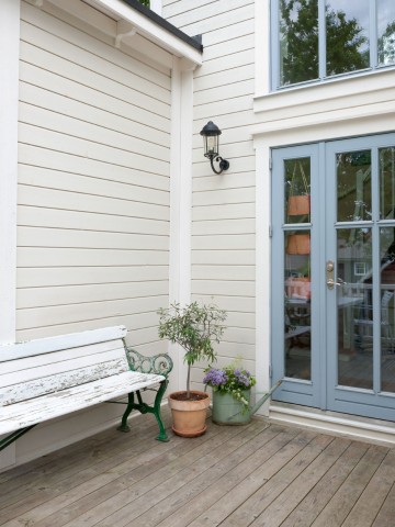 Ett nyvättat grått trähus med terrass